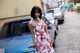 A woman leaning on the hood of a blue car.