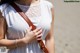 A woman in a white dress holding a brown bag.