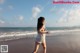 A woman in a white dress walking on the beach.