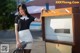 A woman in a black and white uniform holding a gas pump.