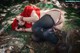 A woman in a red dress is laying on a rock.