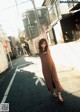 A woman in a brown dress standing in the middle of a street.