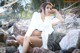 A woman in a white kimono sitting on a rock.