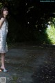 A woman in a white dress standing on a dirt road.