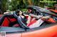 A woman sitting in the driver's seat of a red sports car.