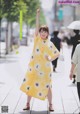 A woman in a yellow dress is walking down the street.