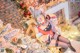 A woman dressed as a reindeer sitting in front of a Christmas tree.