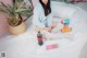 A woman sitting on a bed next to a bottle of soda.