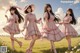 A group of young women in pink dresses and hats walking in a field.