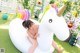 A woman sitting on an inflatable unicorn in a backyard.