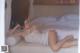 A woman laying on a bed in a white lingerie.